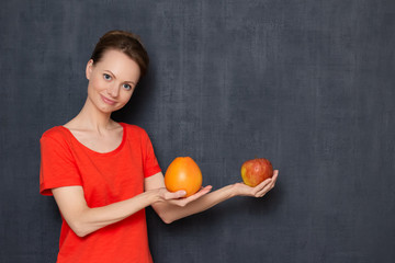 Portrait of happy young woman smiling and holding grapefruit and apple