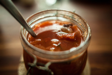 Top view closeup shot of sweet vegetarian healthy classic Indian recipe with fruits.Selective focus of full opened jar with ready to eat chutney fruits and a metal spoon inside.