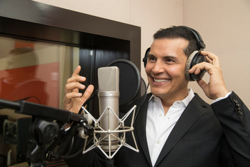 actor and radio announcer with headphones and microphone working film dubbing, performing radio...