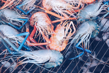 Grilled shrimps on the flaming grill with flames in background in Thailand market