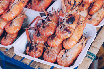 Grilled shrimps on the flaming grill with flames in background in Thailand market