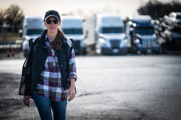 Woman commercial truck driver walking in trucking yard	