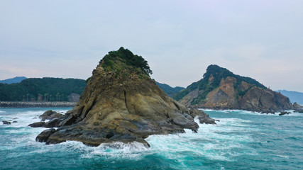 Fototapeta na wymiar rocky islands in the pacific ocean. tropical islands of Japan, a stormy sea of ​​incredible shape cliffs in the ocean. clear turquoise blue water, sea foam