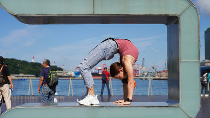 Young flexible girl in life style clothes makes a handstand on observation deck in the passenger port. beautiful gymnast twine on a background of blue sky on sunny day. back bend pose. Handstand poses