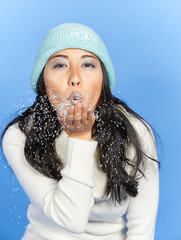 Stunning young Asian woman in winter scene - shot in studio against blue background - wearing thick...