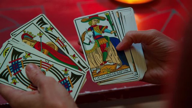 Tarot cards being casually looked at in hands close up, candlelight
