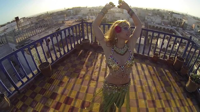 Closeup high angle looking down on belly dancer as she spins on the roof of a building in Morocco at sunset.