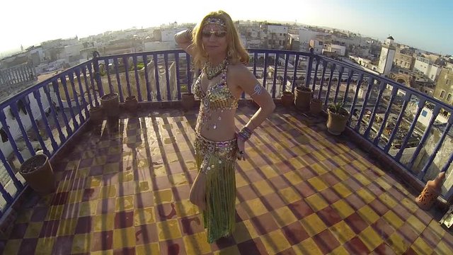 Slow motion of belly dancer at sunset dancing on rooftop in Essaouira, Morocco.