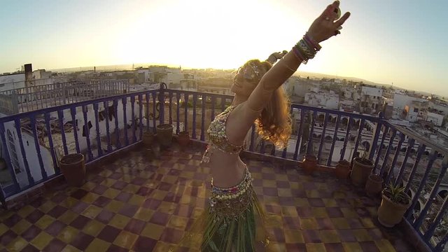 Slow motion of belly dancer with hands in the air and camera above her. Essaouira, Morocco.