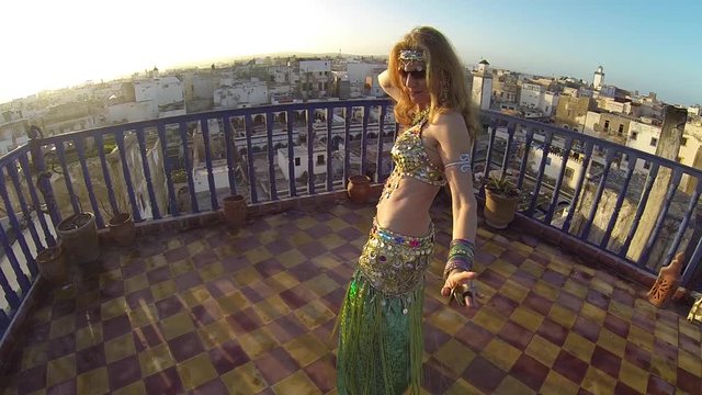 Slow motion of belly dancer at sunset dancing on rooftop in Morocco.
