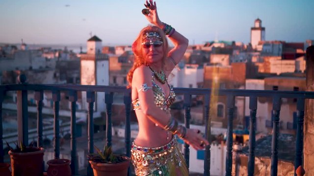 Closeup of blonde belly dancer performing at sunset on a rooftop in Morocco.