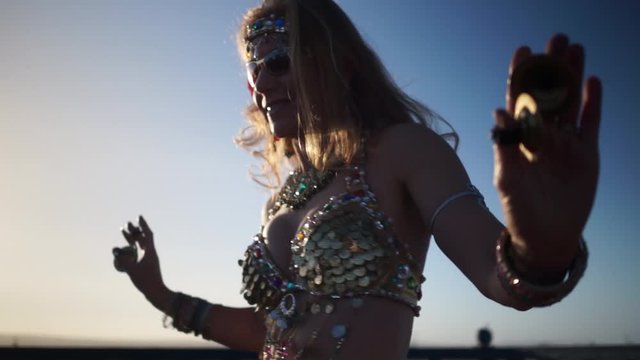 Low angle extreme closeup of backlit belly dancer doing chest shimmies on a rooftop in Morocco.