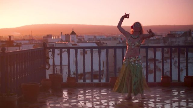 Beautiful belly dancer performing as the sun sets over Essaouira, Morocco.