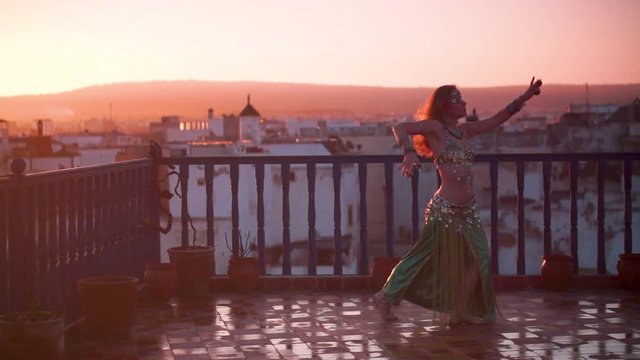 Slow motion of beautiful dancer performing on a rooftop at sunset in Morocco.