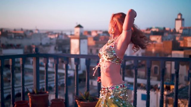Closeup of beautiful belly dancer doing a chest shimmy at sunset on a rooftop in Morocco.
