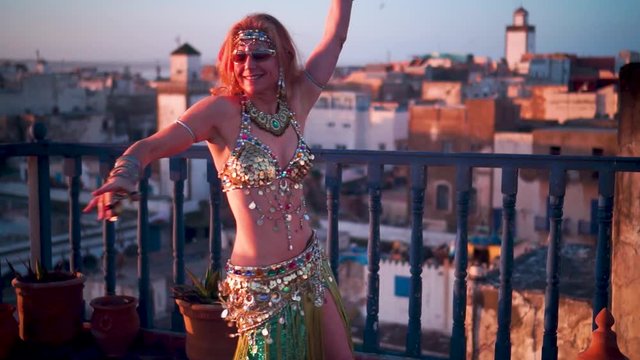 Slow motion of beautiful dancer performing on a rooftop at sunset in Morocco.
