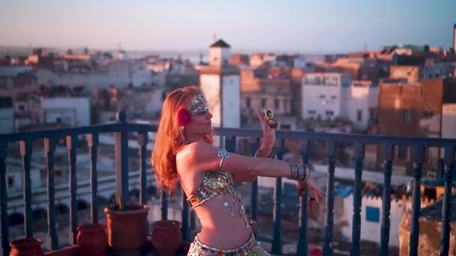 Closeup of beautiful belly dancer doing a chest shimmy at sunset on a rooftop in Morocco.
