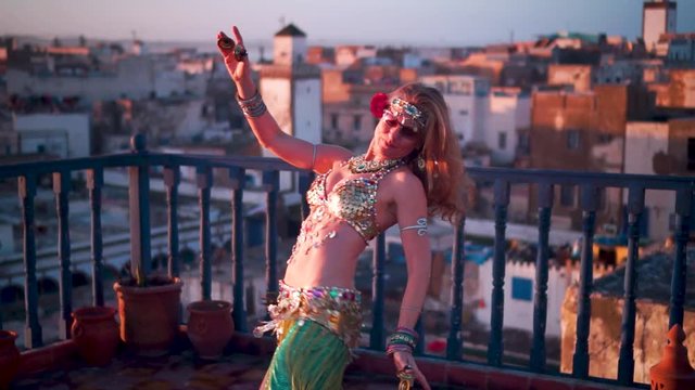 Slow motion of beautiful dancer spinning on a rooftop at sunset in Morocco.