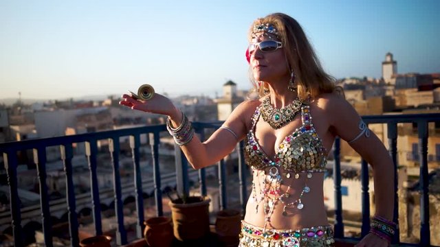 Closeup of beautiful belly dancer doing a hair toss spin at sunset on a rooftop in Essaouira, Morocco.