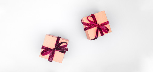 Craft boxes with dark red ribbon bows. Holiday, Christmas, New Year and Valentine day eco-friendly wrapping concept. Trendy minimalistic flat lay design background. Wide screen banner format