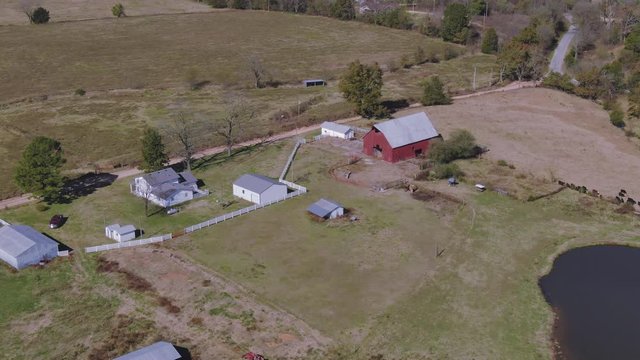 Aerial flyover farmhouse barn beside cow pond