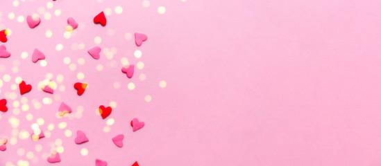 Fototapeta na wymiar Two tone heart sprinkles on the solid pink background with light festive bokeh. Romance, love, Valentines and mother's day concept. Flat lay, horizontal wide screen banner format with place for text