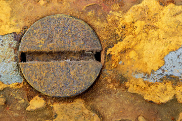 A heavily rusted metal surface shows intense colors. There is a screw in the metal. Concept: textures and backgrounds