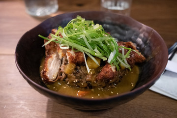 Chicken katsu curry over rice with spring onion on top