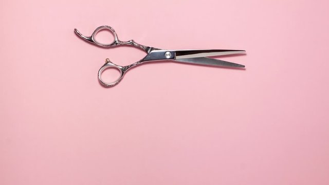 Stop motion animation top view of professional hair cutting shears on pink background. Hairdresser salon equipment concept, premium set