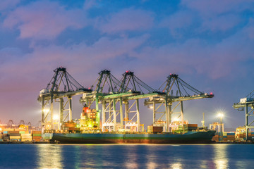 Fototapeta premium Container Cargo freight ship with working crane loading bridge in shipyard at dusk for Logistic Import Export background