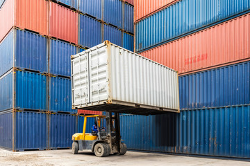 Forklift handling container box loading to freight train in logistics zone