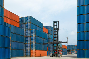Fototapeta premium crane lifting up a container cargo in shipyard for import export in port with logistics area background