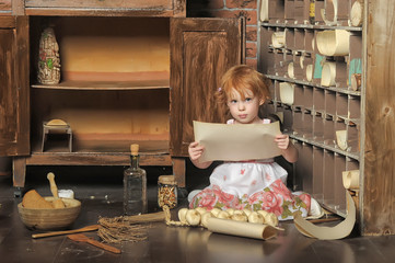 red-haired girl with a sheet of paper in her hands in a vintage pantry plays