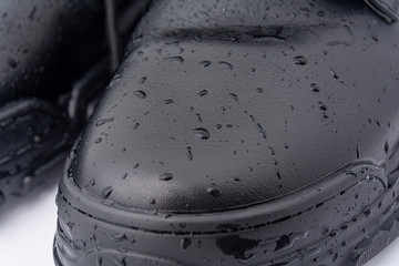 Drops of water on black leather shoes. Concept: processing and care of shoes, water-repellent...