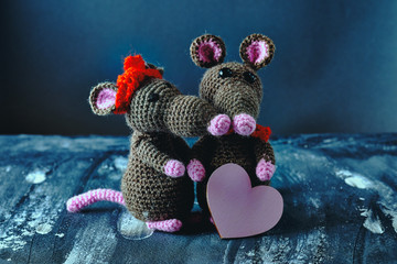 Lovely handcrafted amigurumi mouse hugs another when it holding a pink heart. Valentine day, February 14, love, relations concept
