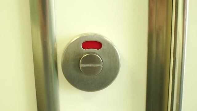 Close-up of a toilet door lock with a red closed sign switches to a green open sign. Slow motion.