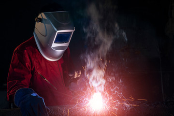 worker welding a part of metal in welding workshop industrail with welding lighting