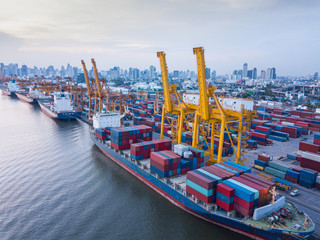 Aerial view of container ship loading containers by working crane in port terminal with container...
