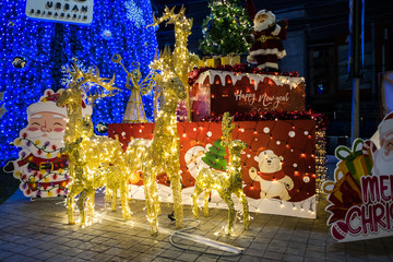 Christmas tree decorations with evening light illumination with deer made of lamps.