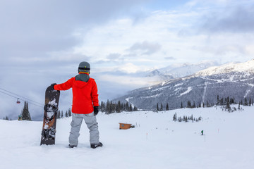 Fototapeta na wymiar Male Snowboarder is riding down a ski run in wintertime. Taken on Whistler Mountain, British Columbia, Canada.