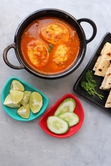 Indian non-vegetarian food- Homemade Egg Curry or Anda masala gravy, Indian spicy food, along with Roti, Lemon wedges and cucumber slices. Perfect Indian lunch. over light background with copy space.