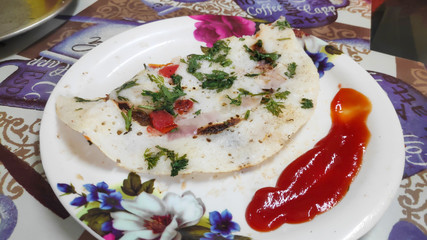 Utthapam dish garnished with ketchup 