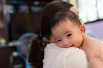 mother holding an infant baby on her right side, embracing baby girl in her arms, baby resting on mom's shoulder, love and care concept