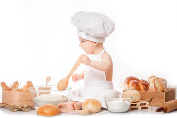 little boy in a cook costume among a baking bread rolls of flour confectionery. Copy space