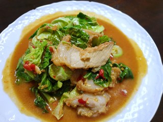 Top view of stir fried cabbage chick topping with fried crispy pork in white plate as a background in restaurant, Healthy food concept, Ready to eat or serve