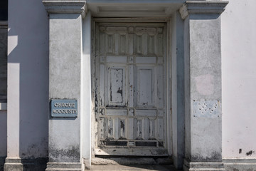 The main entrance to an abandoned bank building, with a "Cheque accounts" sign on a pillar. Tokomaru Bay, East Cape, New Zealand. 