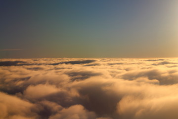evocative image of white clouds with blue sky and sea in the background seen from a plane