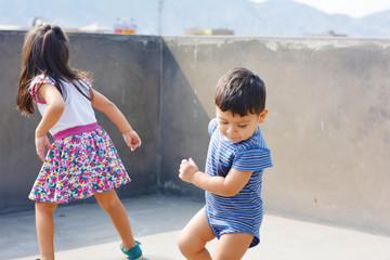 Active little latin siblings playing outside.