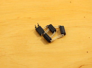 Electronic components. Optocoupler with four pins on wooden background. Microchip.