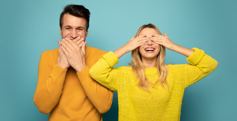 No speak, no see. Close up photo of happy excited man and woman, who are posing with their hands covering their mouth and eyes.